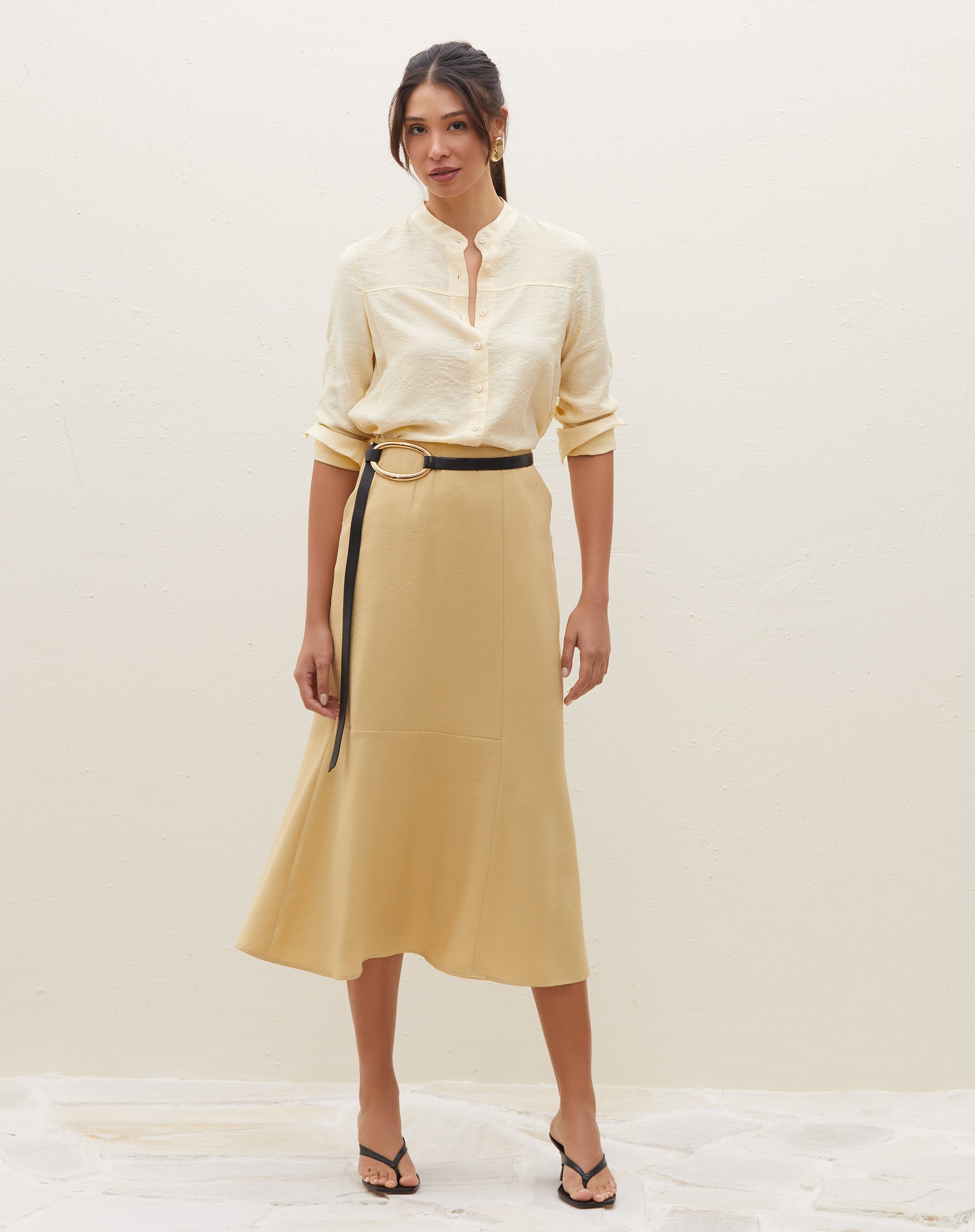 Modelo vestindo saia midi com recortes na cor areia, vista frontal.