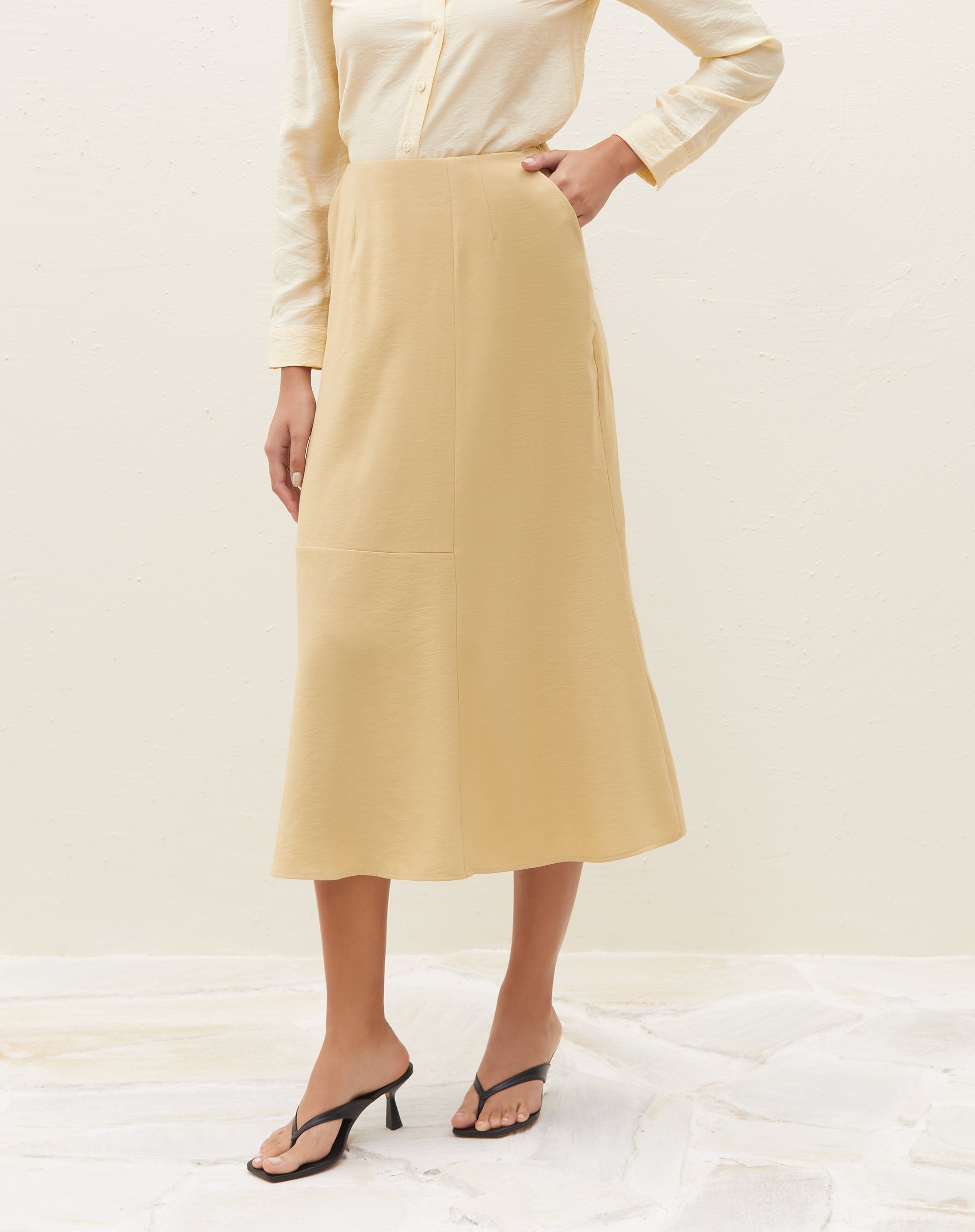 Detalhe lateral da saia midi com recortes na cor areia.