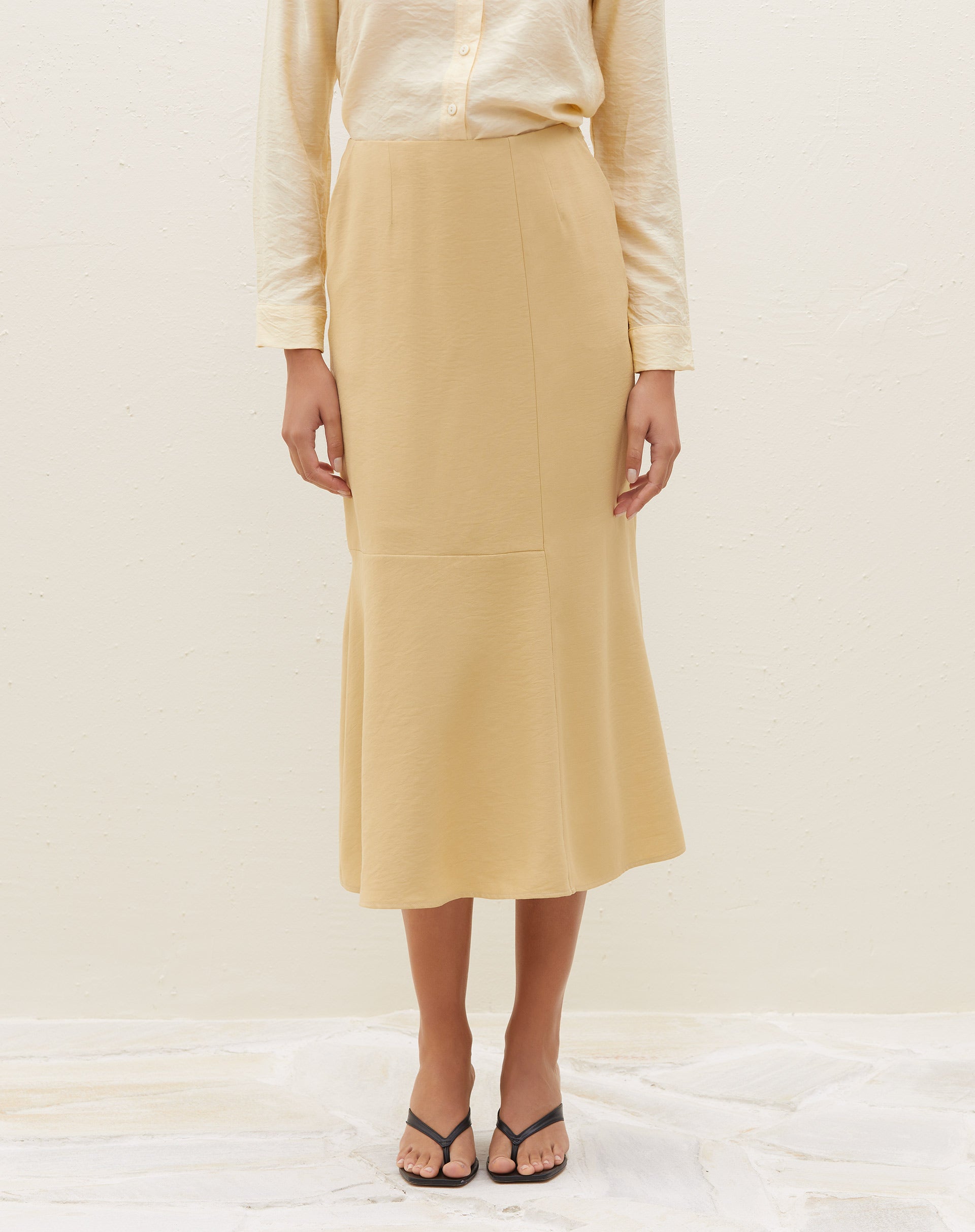 Close-up da saia midi com recortes na cor areia, mostrando detalhes do tecido.
