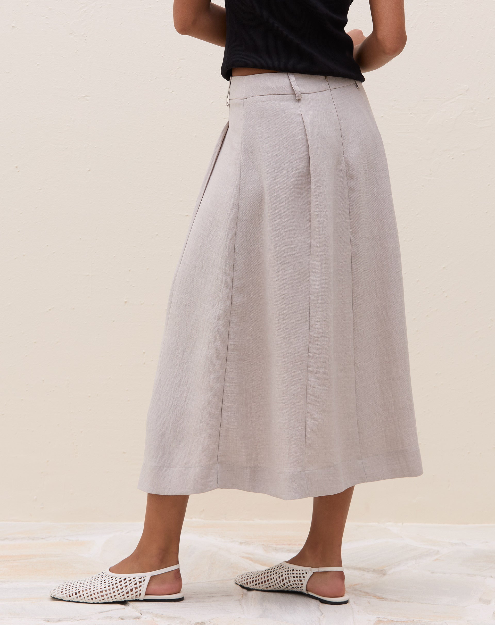 Vista lateral da saia midi cinza claro com pregas.