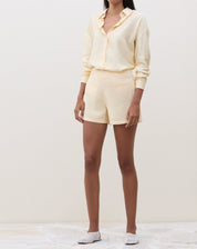 Modelo vestindo camisa manga longa em tecido manteiga, combinada com shorts.