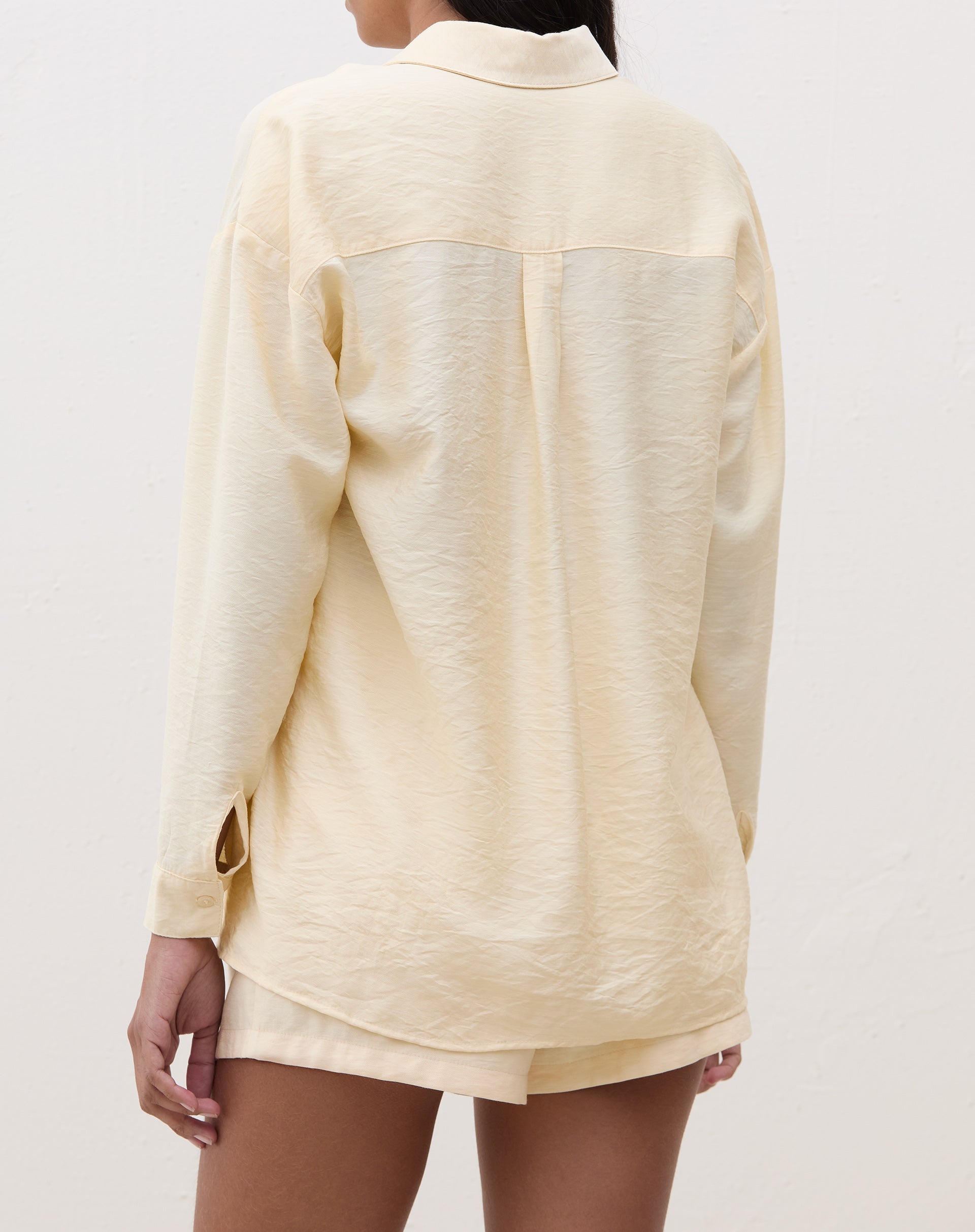 Vista traseira da camisa manga longa em tecido manteiga, mostrando detalhes do corte.