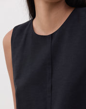 Close-up do decote redondo e recorte frontal da regata preta.