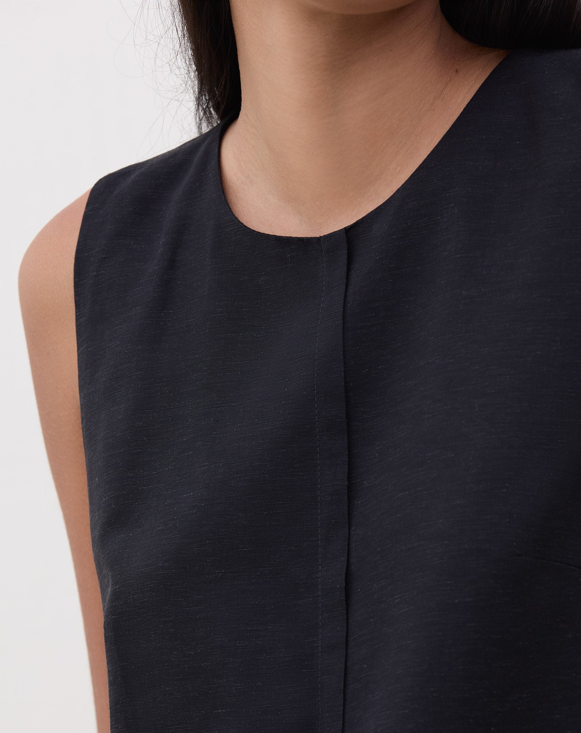 Close-up do decote redondo e recorte frontal da regata preta.