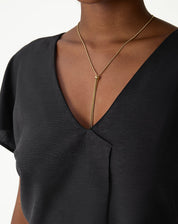 Detalhe do decote V da blusa preta.