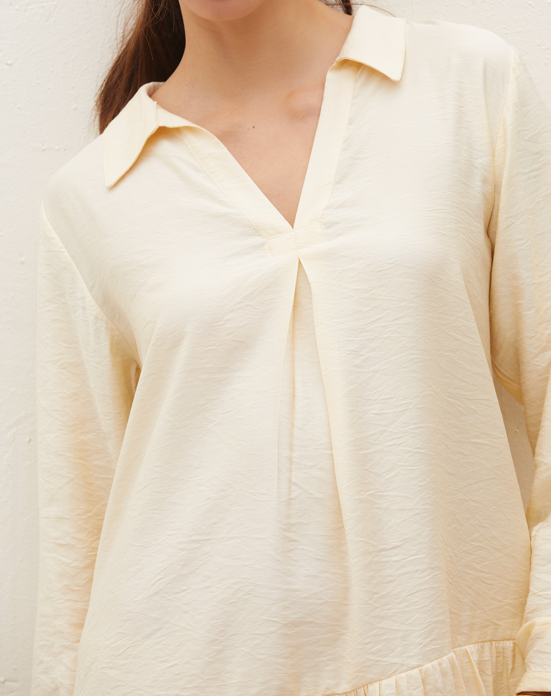 Detalhe da gola diferenciada do vestido curto em tom manteiga.