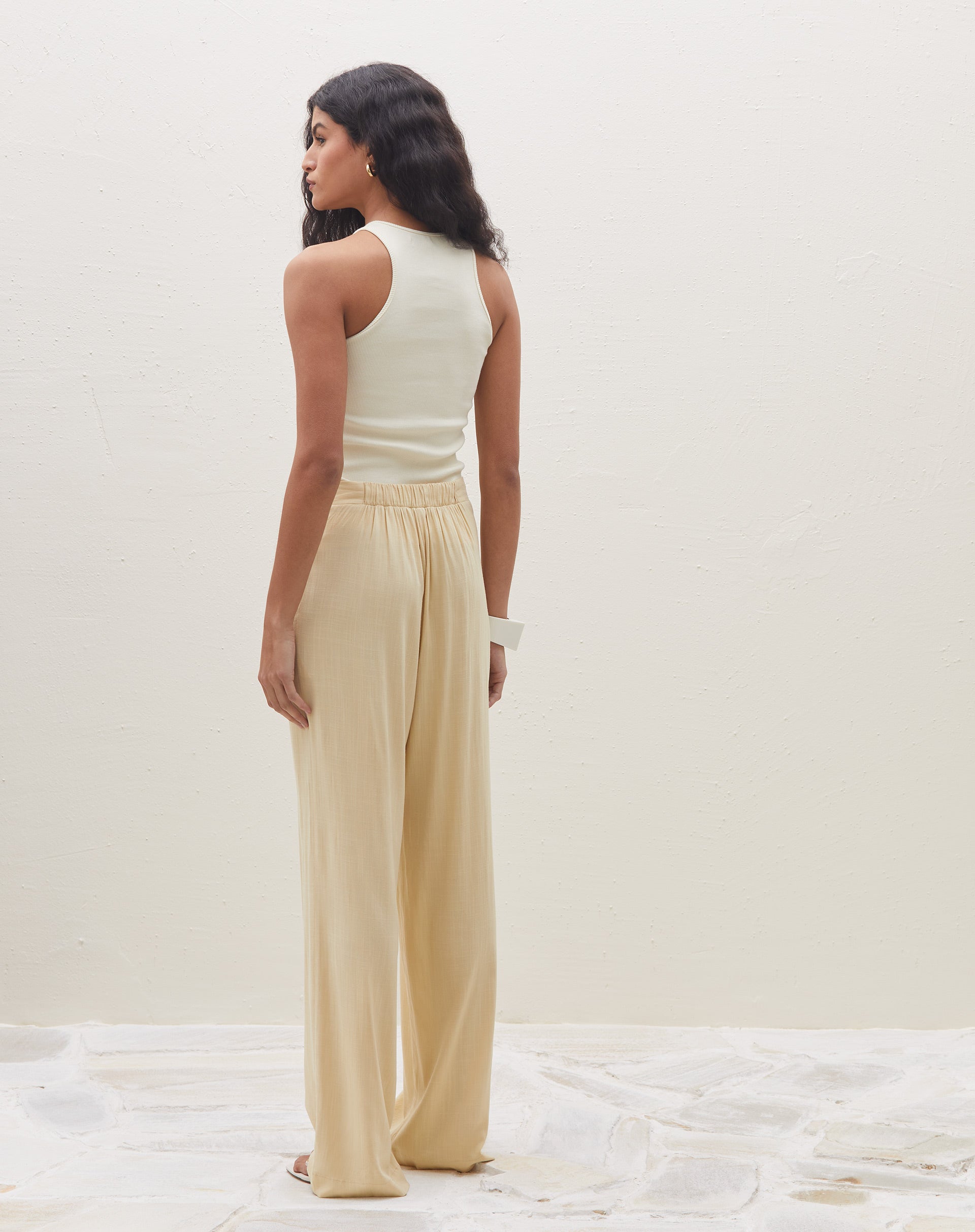 Vista lateral da calça reta de cintura alta na cor areia.