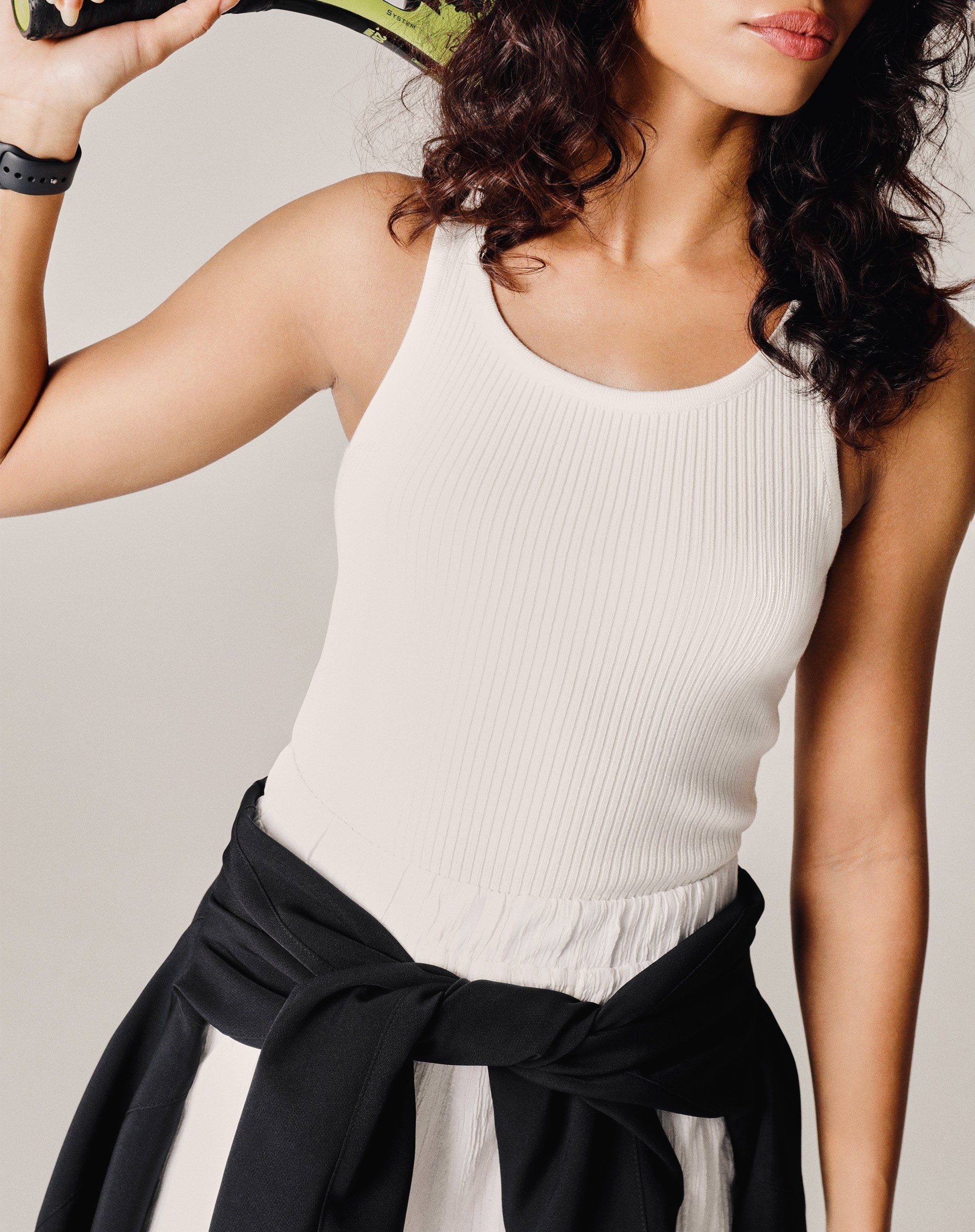 Modelo vestindo shorts branco com cintura alta e elástico, combinado com blusa preta.