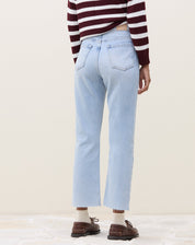 Modelo vestindo calça reta cropped jeans azul claro com bainha aplicada.