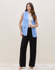 Modelo vestindo o colete de alfaiataria azul médio com calça preta.