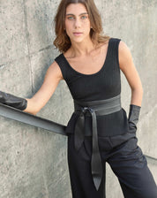 Modelo vestindo calça Wide Leg preta com pregas, combinada com top preto sem mangas.