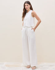Modelo vestindo calça wide leg off-white com pregas, vista frontal.