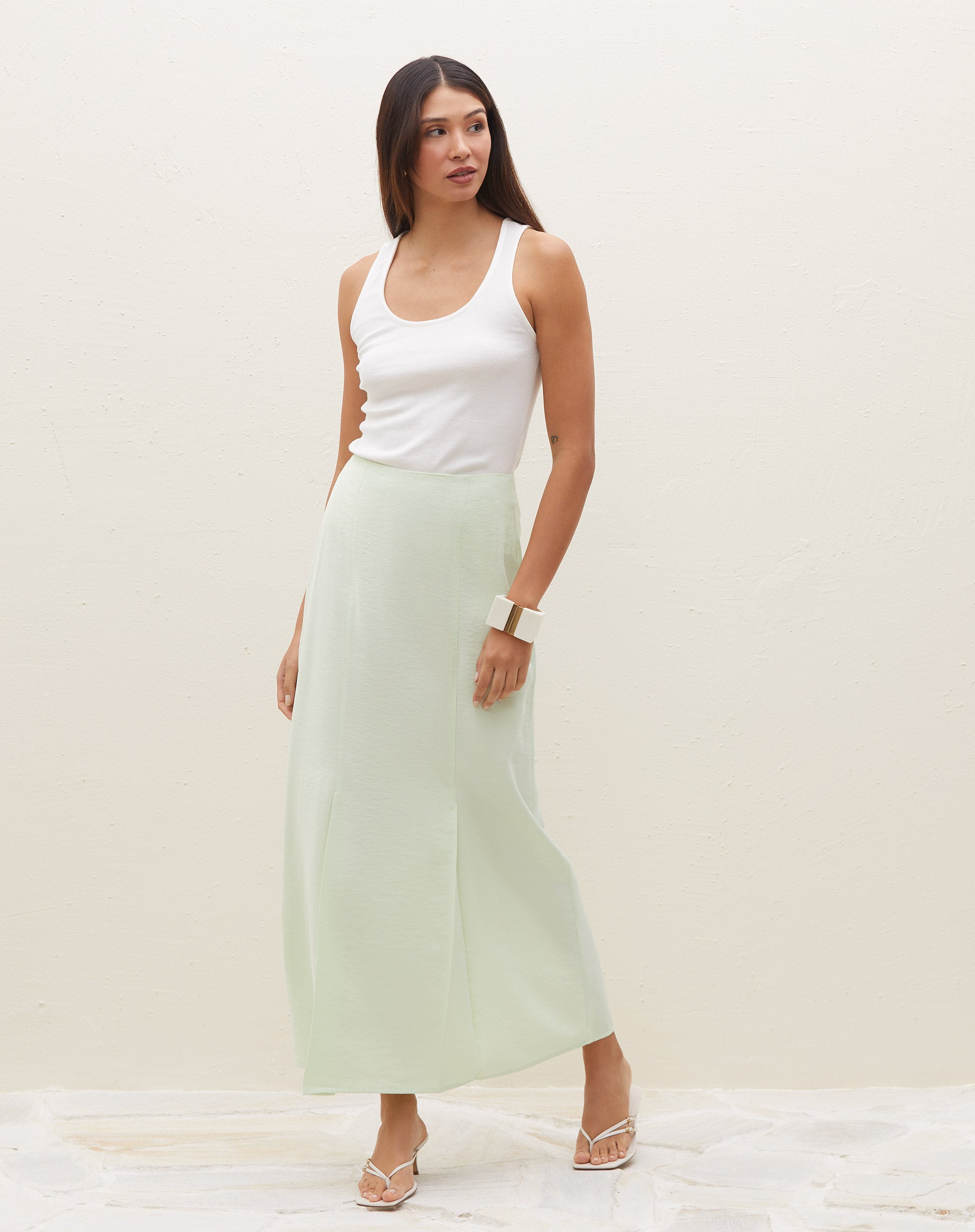 Modelo vestindo saia midi verde claro com pregas, vista frontal.