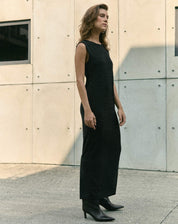 Modelo vestindo vestido midi preto com fenda, em ambiente urbano.