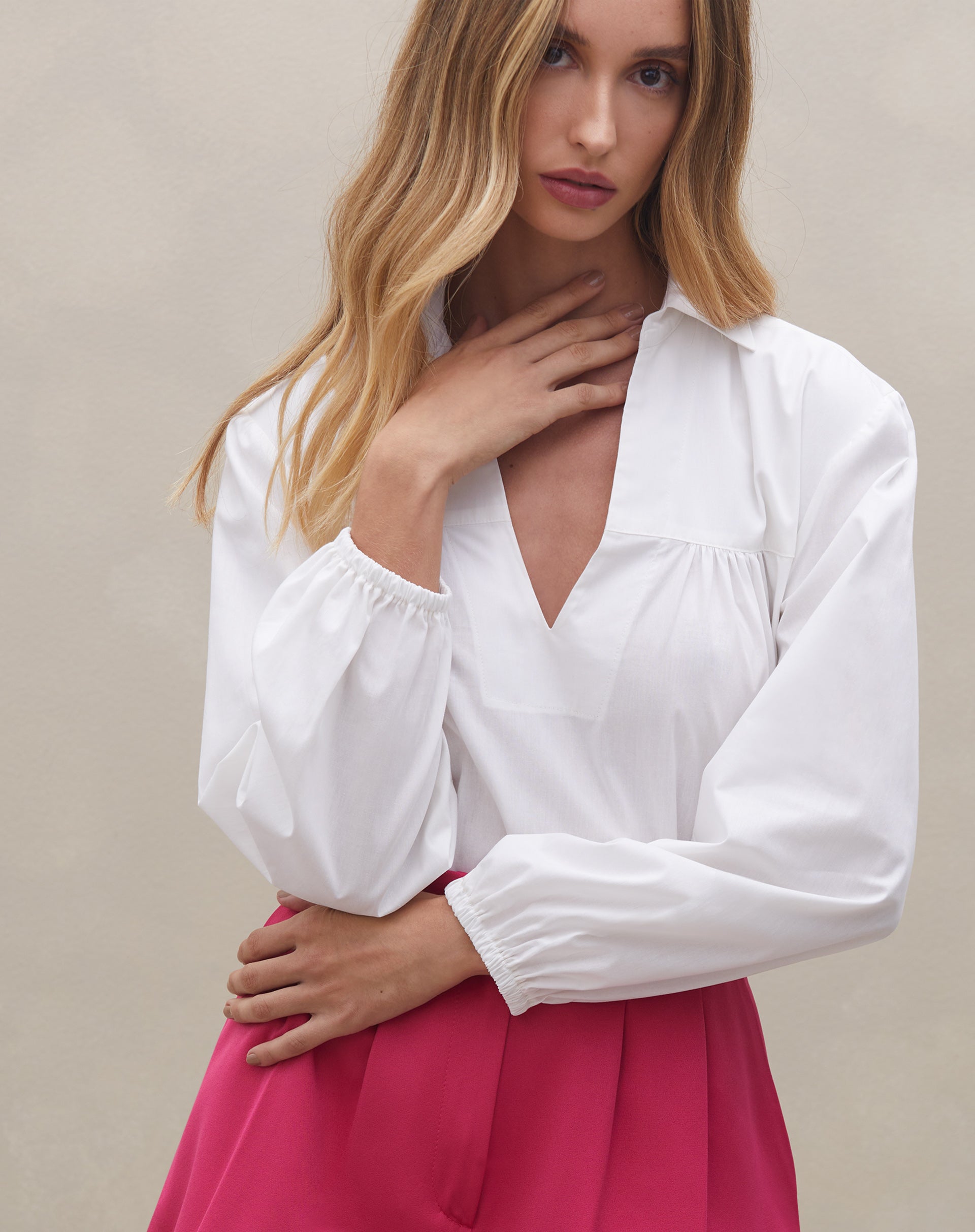 Detalhe da camisa branca com decote em V, complementando o shorts rosa.