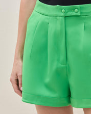 Vista traseira do shorts de alfaiataria verde, destacando o ajuste e os bolsos.