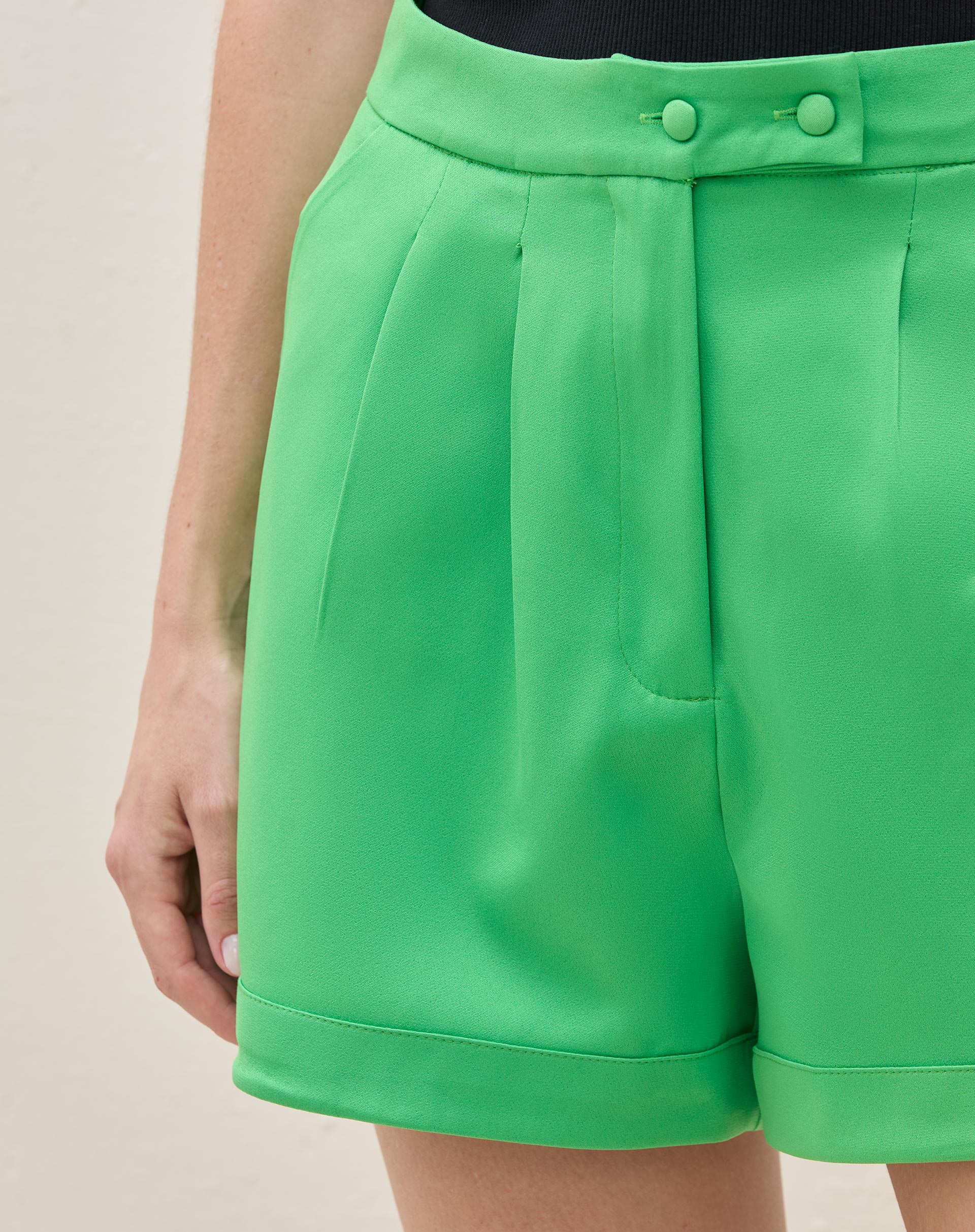 Vista traseira do shorts de alfaiataria verde, destacando o ajuste e os bolsos.