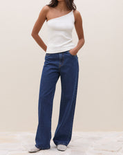 Modelo vestindo a blusa um ombro só de ribana power off-white com calça jeans.