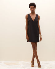 Modelo vestindo um vestido curto preto com decote V na frente, vista frontal.