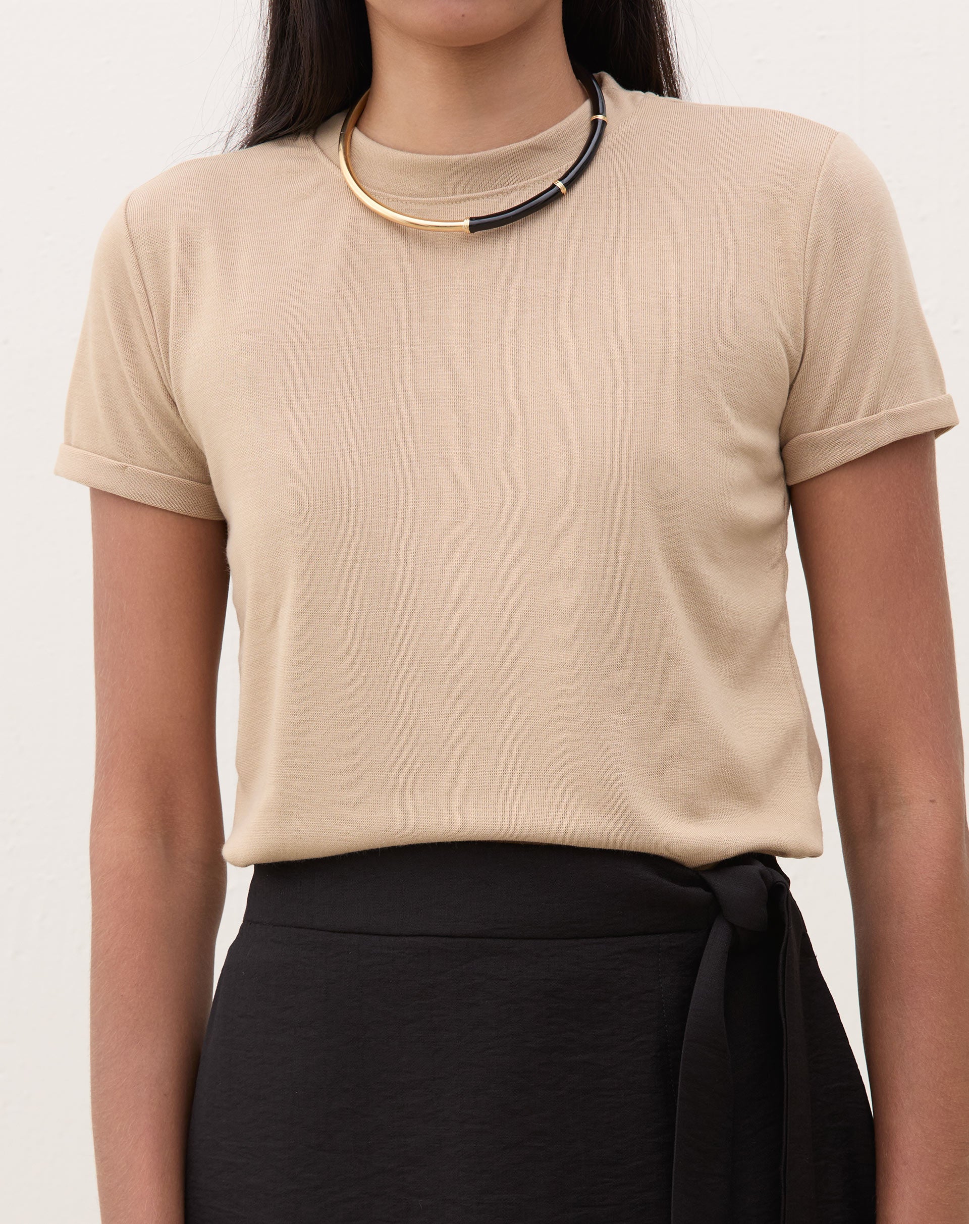 Camiseta de malha bege com mangas curtas dobradas, vista frontal.