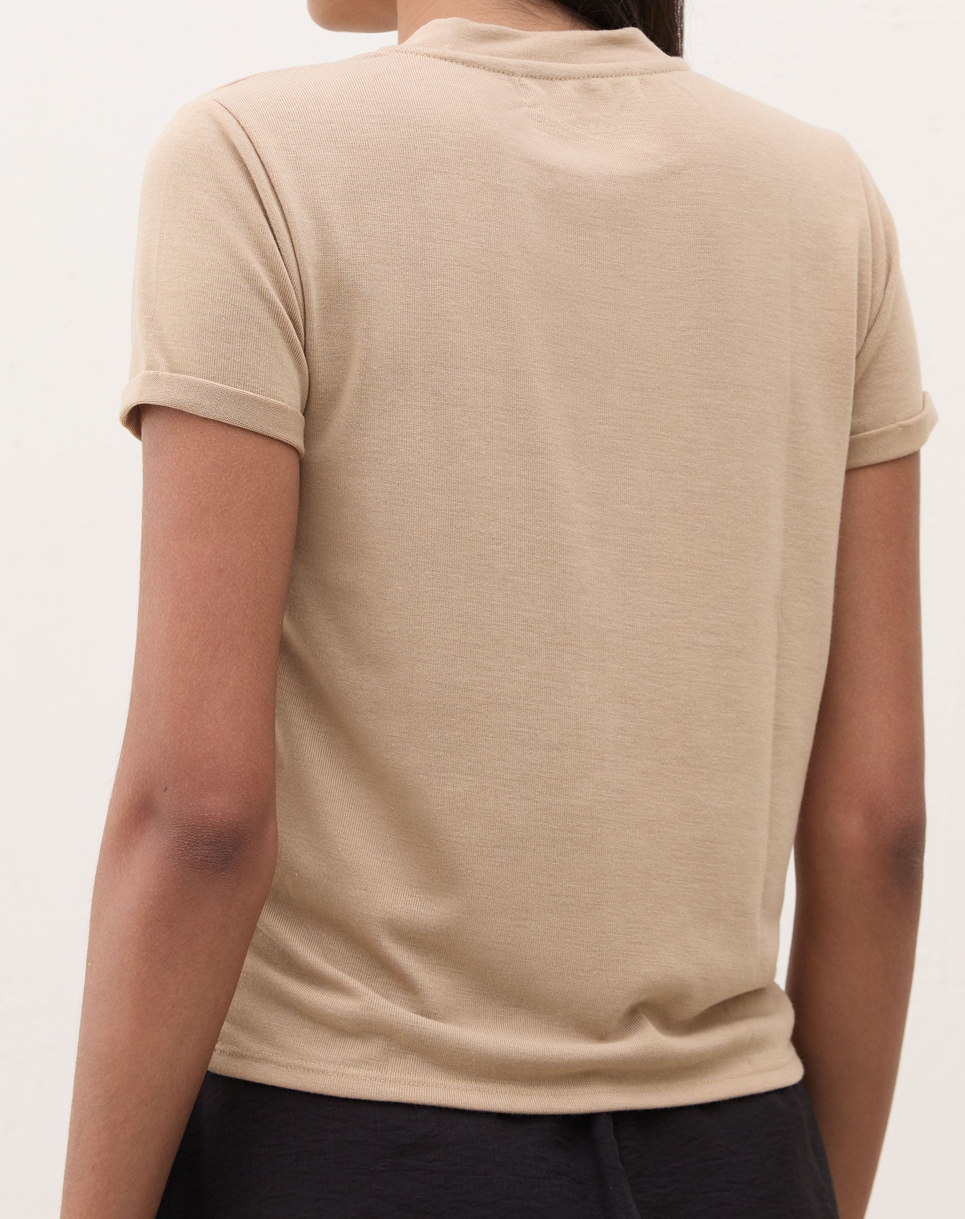 Modelo vestindo a camiseta bege com saia preta.