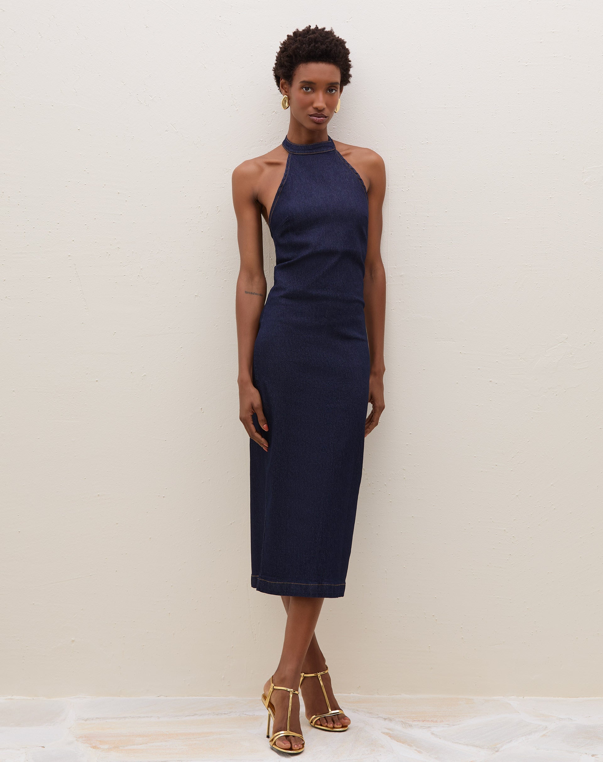 Modelo vestindo vestido midi azul escuro com decote fechado e tecido jeans, posando de frente.