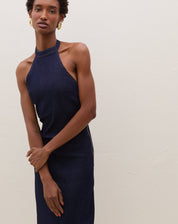 Modelo vestindo vestido midi azul escuro com decote fechado e tecido jeans, posando com braços cruzados.