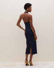 Modelo vestindo vestido midi azul escuro com decote fechado e tecido jeans, posando de costas.