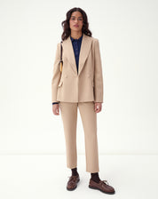 Conjunto completo com blazer e calça bege de alfaiataria em styling formal sobre fundo branco.