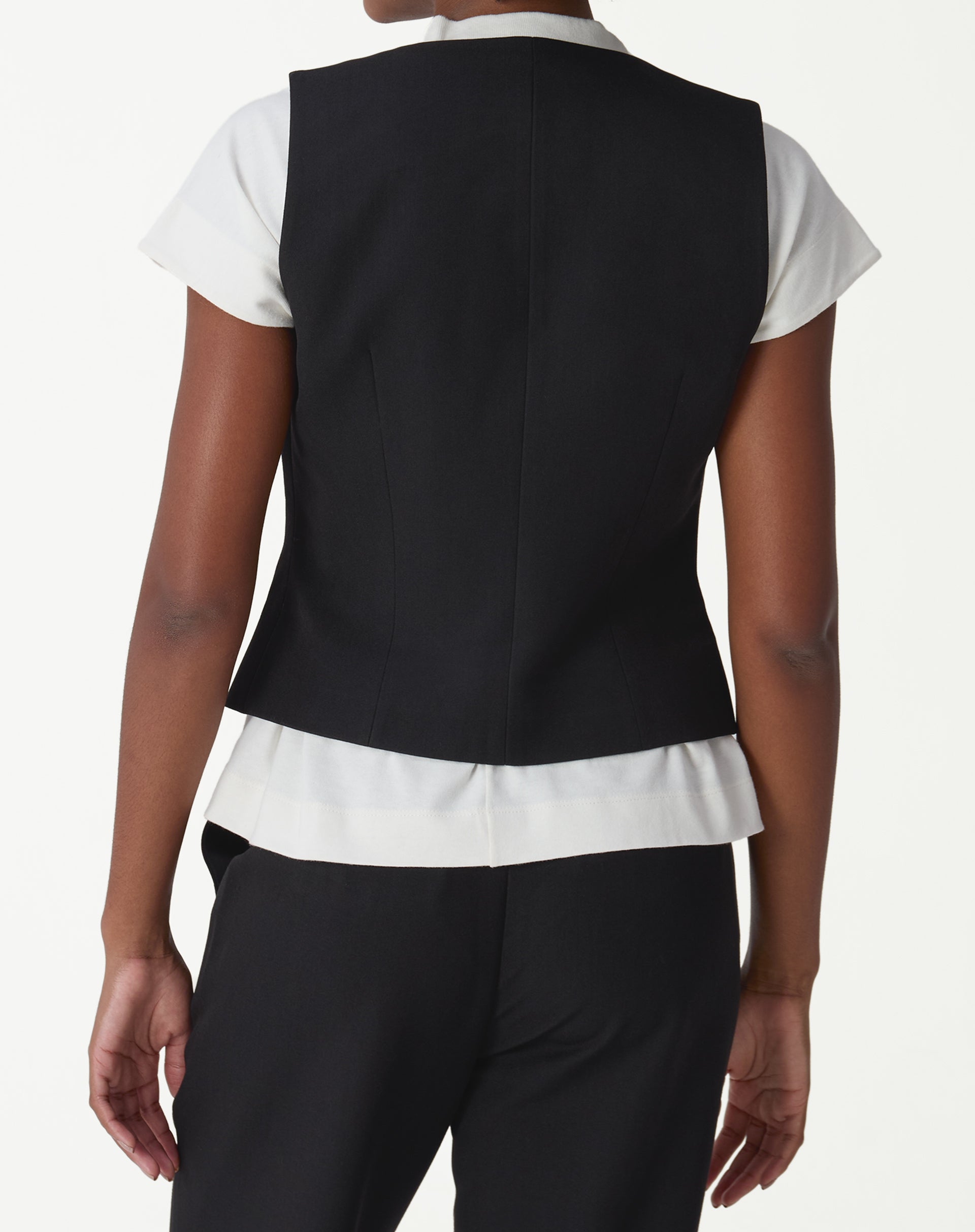 Vista traseira do colete alfaiataria preto em modelo, evidenciando corte ajustado e comprimento midi.