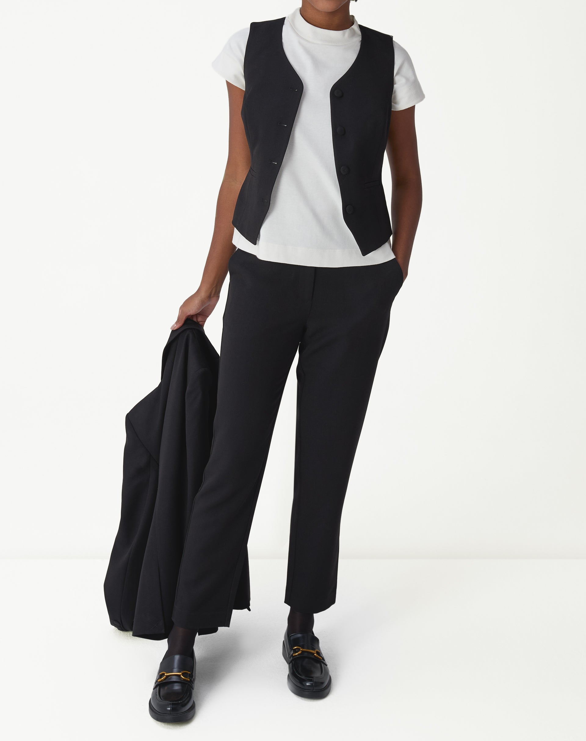 Look completo: modelo usando colete slim alfaiataria preto com camiseta branca e calça social preta, visual office-to-evening.