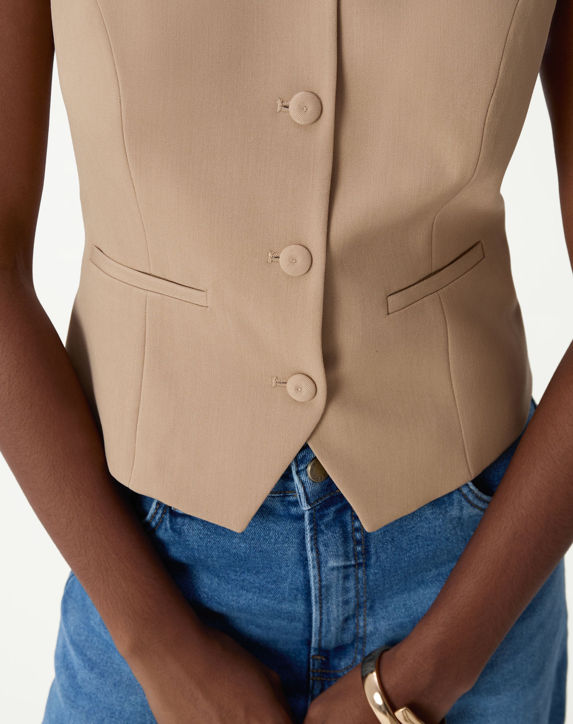 Vista traseira do colete slim bege mostrando costuras da modelagem e caimento estruturado em tecido plano