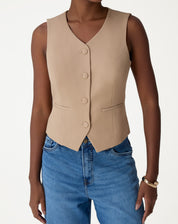 Close-up do painel frontal com botões forrados e bolsos embutidos do colete alfaiataria bege, detalhe de acabamento