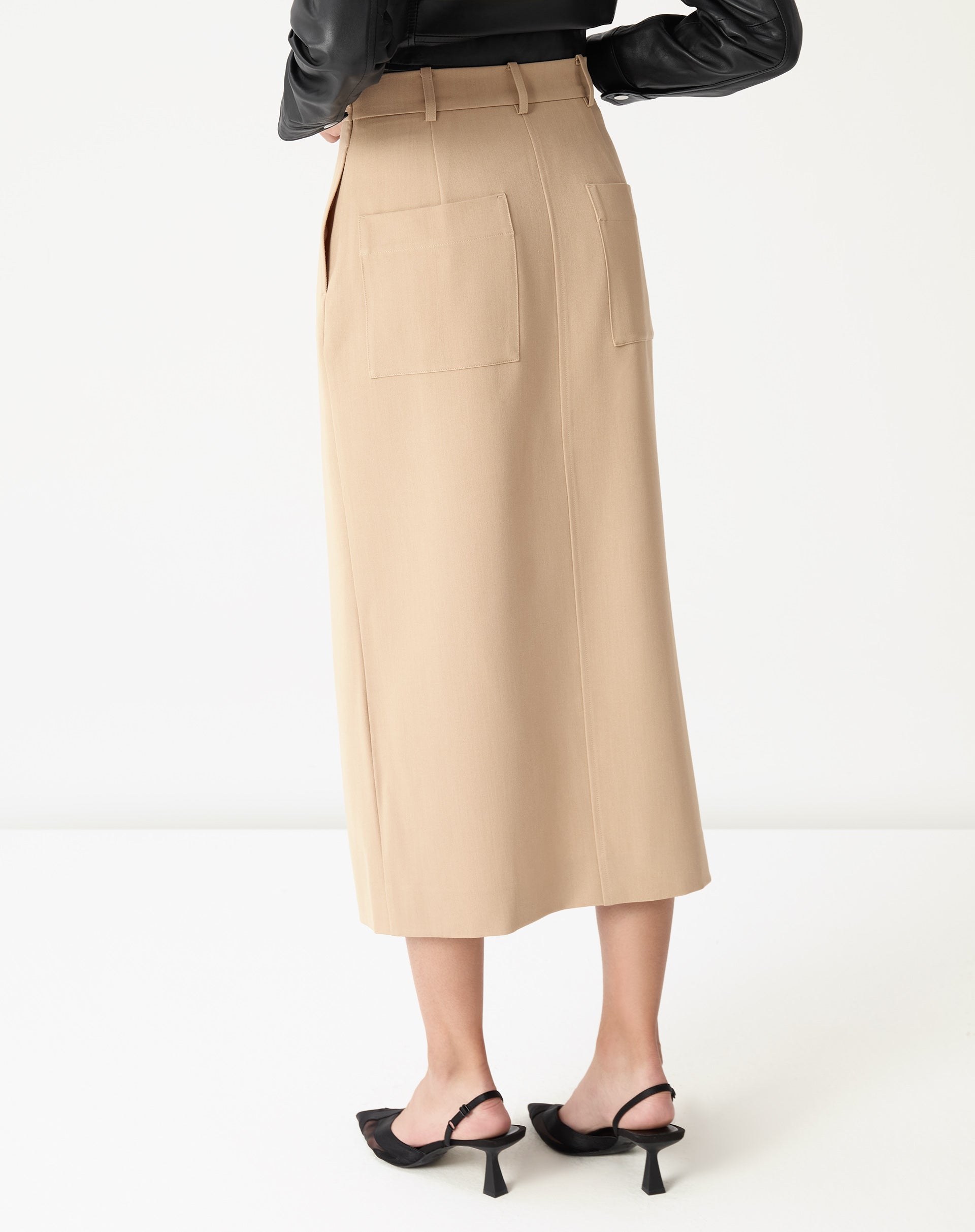 Vista frontal inferior da saia midi alfaiataria bege destacando a fenda frontal discreta e o caimento reto até o meio da canela