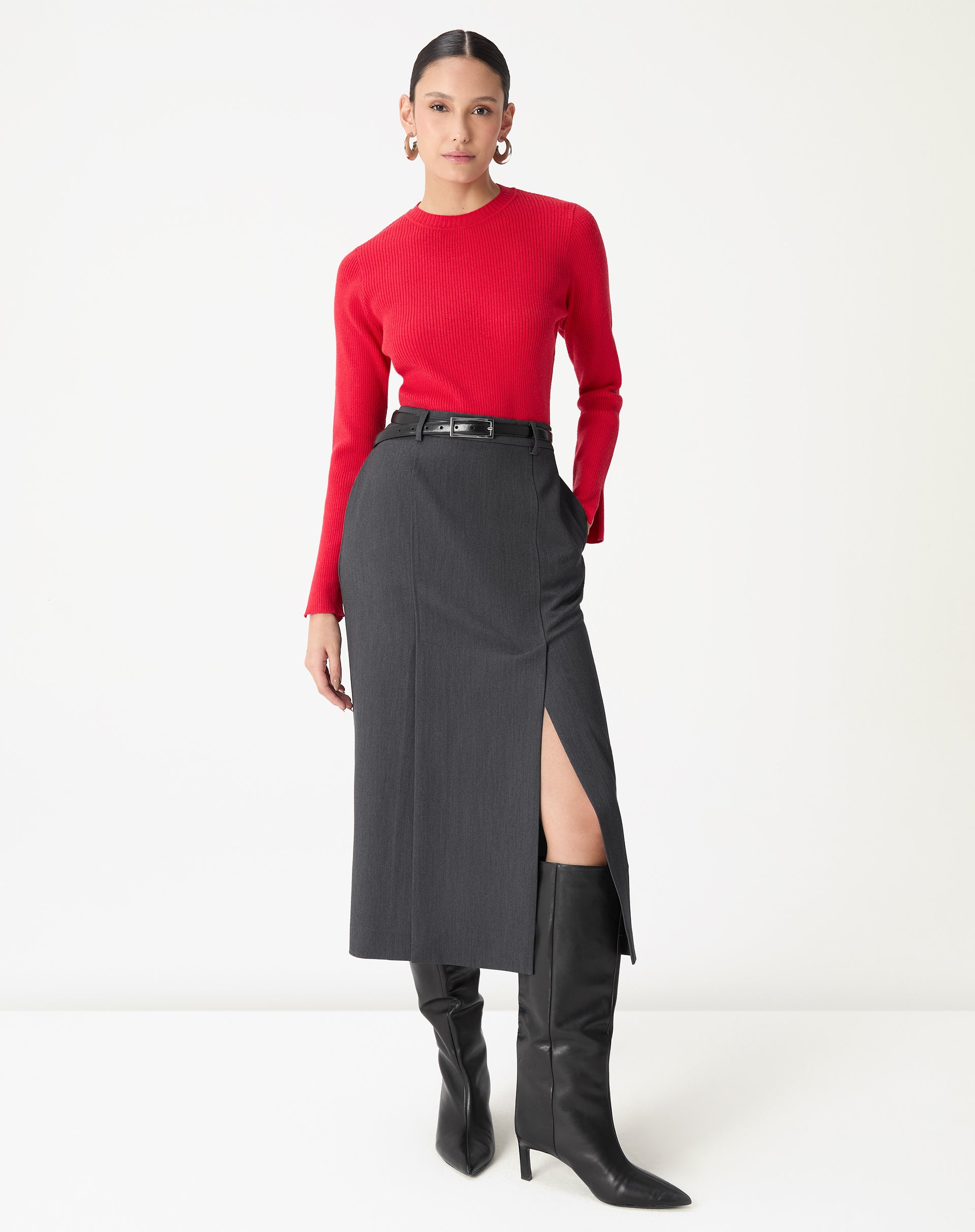 Saia midi alfaiataria cinza com fenda lateral vista frontal em modelo usando suéter vermelho e botas pretas, destacando corte reto e cós médio.