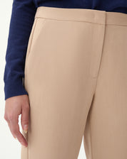 Vista flatlay da calça slim alfaiataria bege sobre fundo branco, destacando comprimento cropped e corte reto.