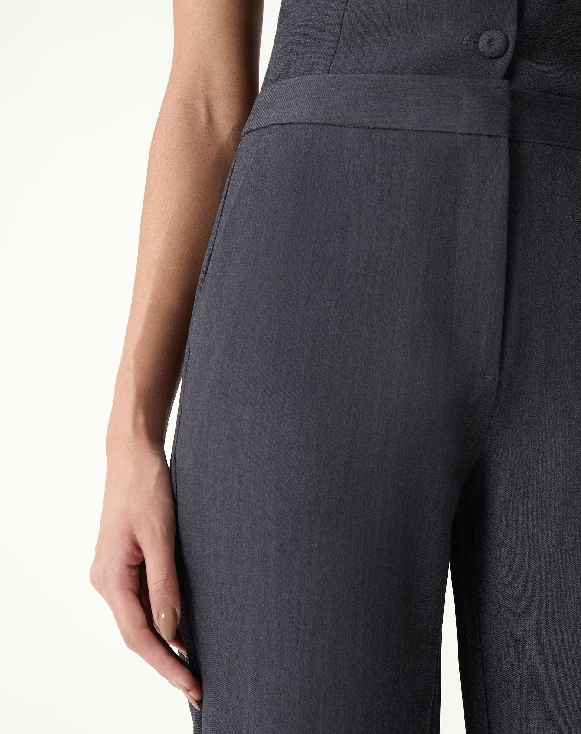 Calça slim alfaiataria cinza vista lateral 3/4 com mãos nos bolsos, corte reto e comprimento longo