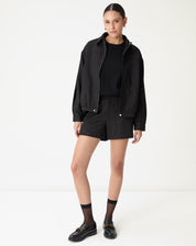 Close do corpete frontal do casaco preto destacando a costura horizontal e o corte de alfaiataria