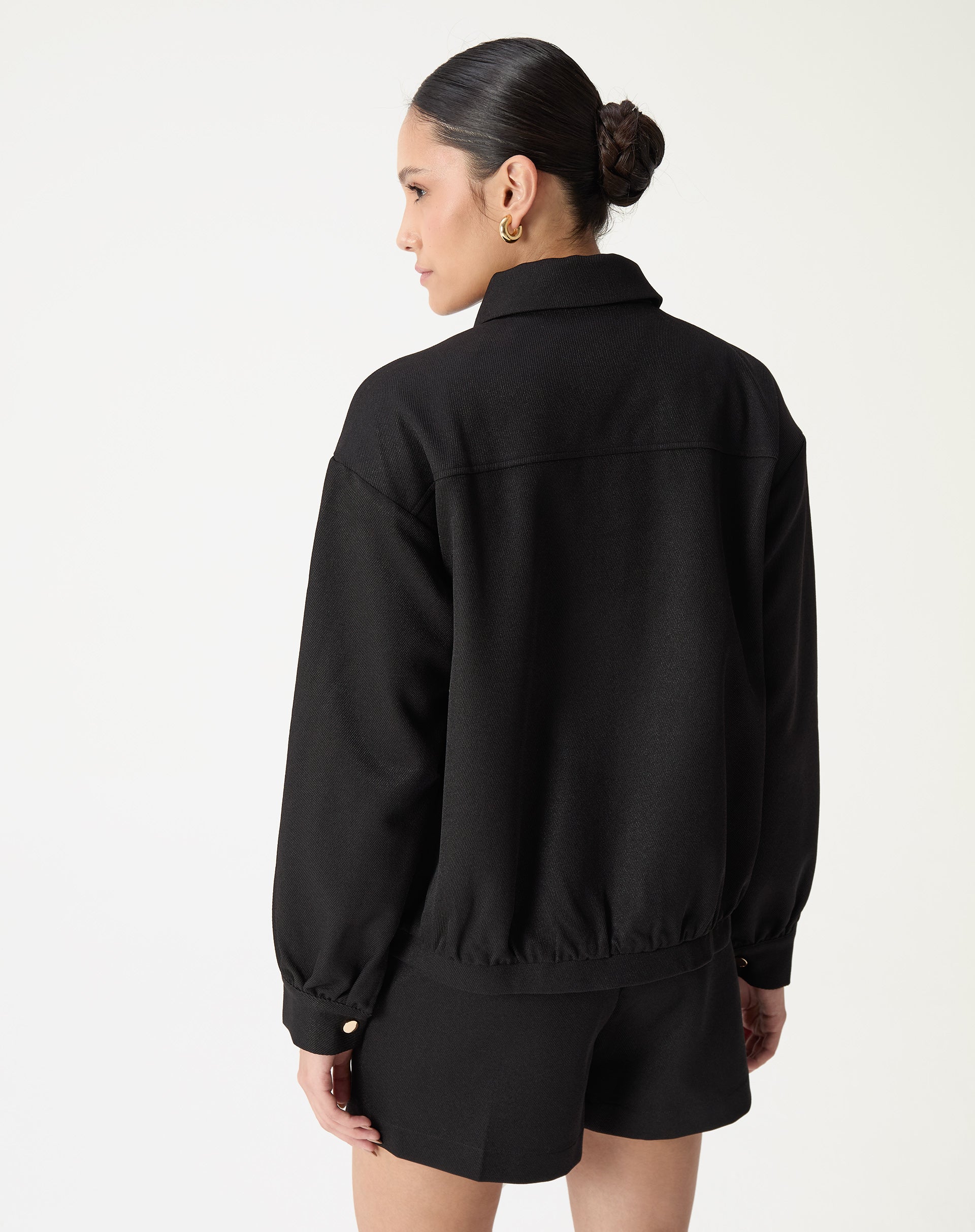 Close do colarinho clássico e do botão de pressão metálico na barra do casaco preto, detalhe do tecido plano