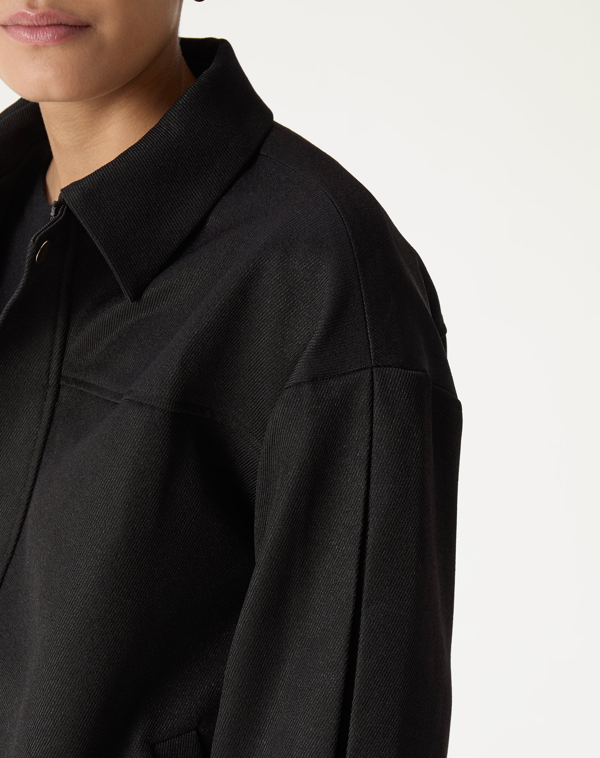 Verso do casaco preto com painel traseiro e pala, vista do caimento e do ombro
