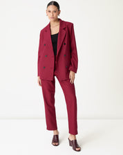 Modelo em pé vestindo blazer oversized vinho longo com calça reta combinada e top preto, visual completo frontal.