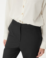 Close do cós frontal da calça preta evidenciando acabamento limpo e fecho invisível