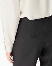 Detalhe traseiro da calça preta mostrando bolso jato embutido e costura limpa