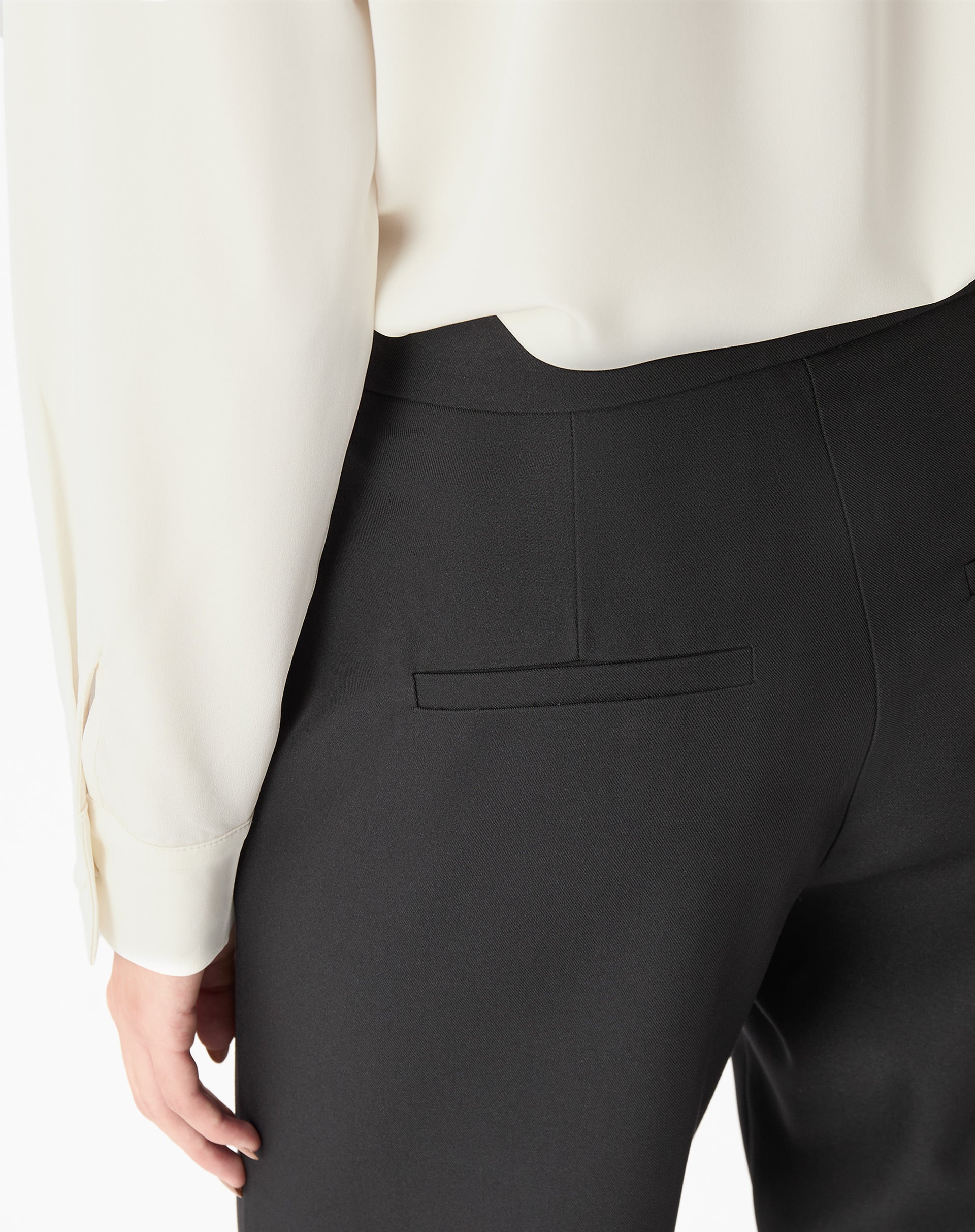 Detalhe traseiro da calça preta mostrando bolso jato embutido e costura limpa