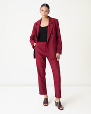 Modelo vestindo conjunto alfaiataria vinho: blazer de abotoamento duplo e calça slim reta cintura alta - look formal e contemporâneo
