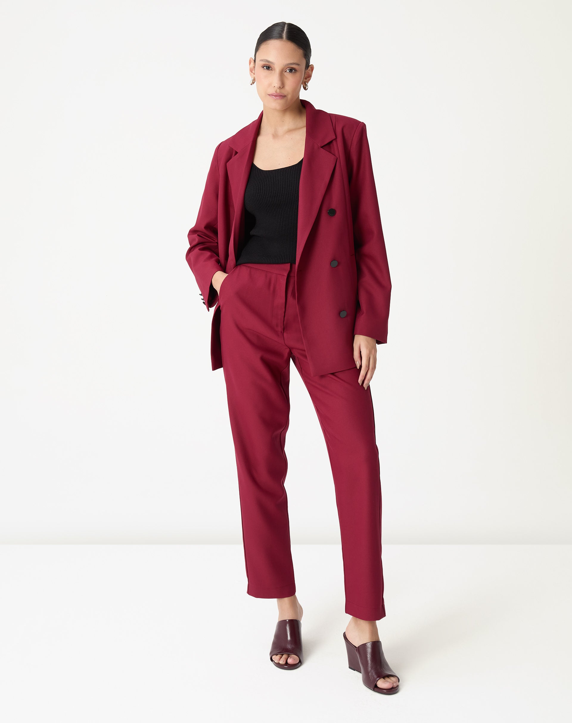 Modelo vestindo conjunto alfaiataria vinho: blazer de abotoamento duplo e calça slim reta cintura alta - look formal e contemporâneo