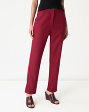 Detalhe frontal da calça alfaiataria vinho mostrando cós alto, pala frontal e bolso faca com acabamento liso