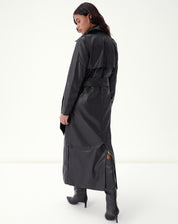 Close do torso do trench coat em PU preto exibindo pala frontal, bolso embutido e cinto amarrado com nó discreto.