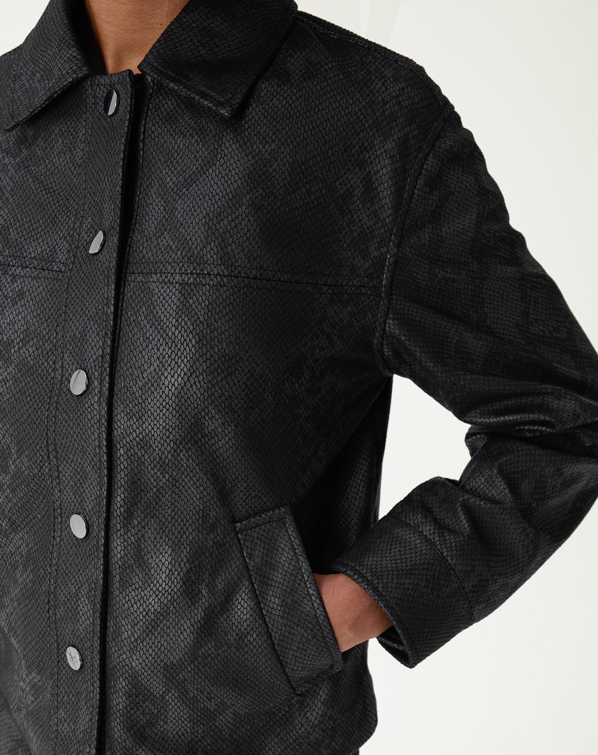 Imagem de detalhe destacando textura de escamas na jaqueta, com bolso e design minimalista.