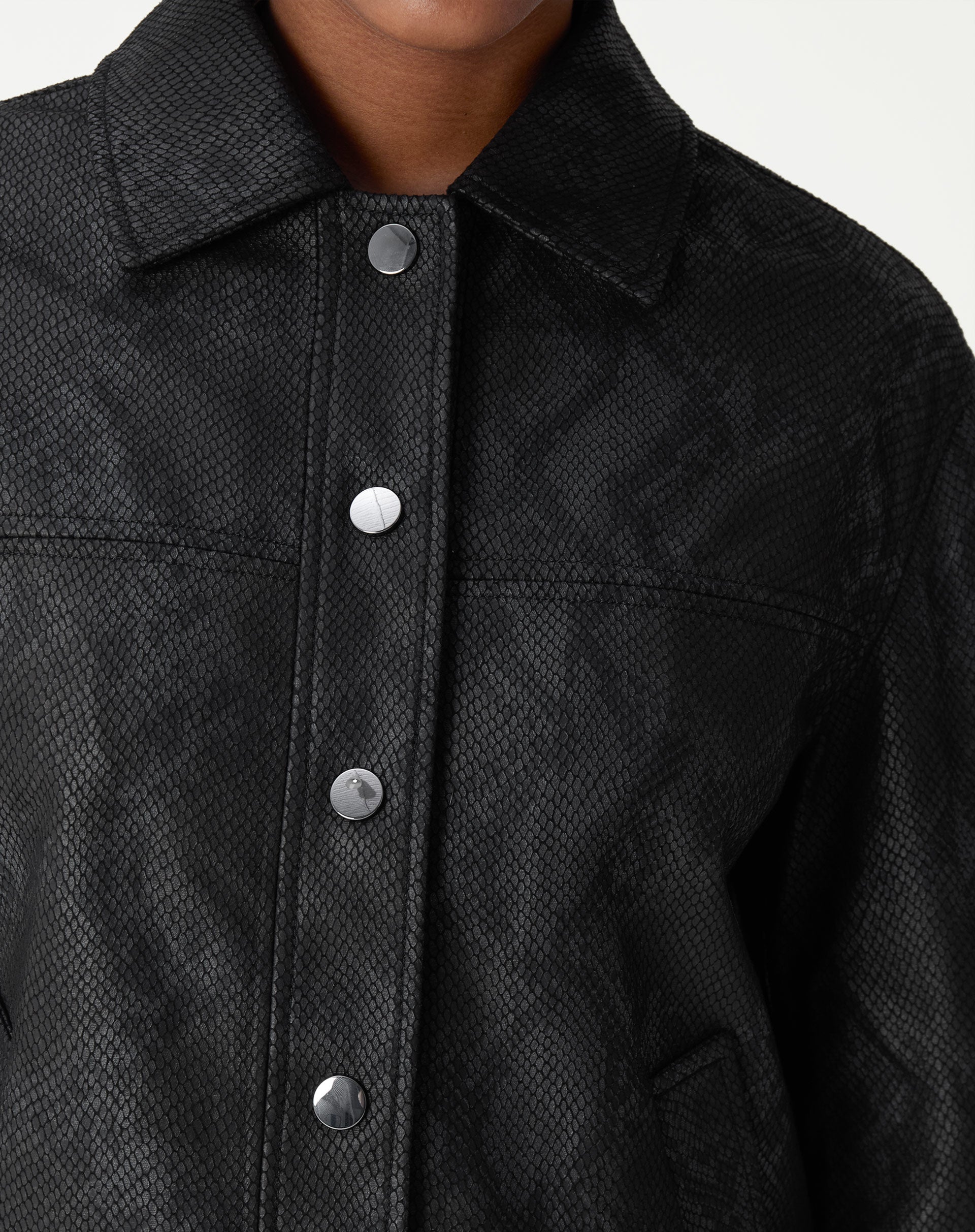 Detalhe de fechamento da jaqueta com botões de pressão em acabamento fosco.